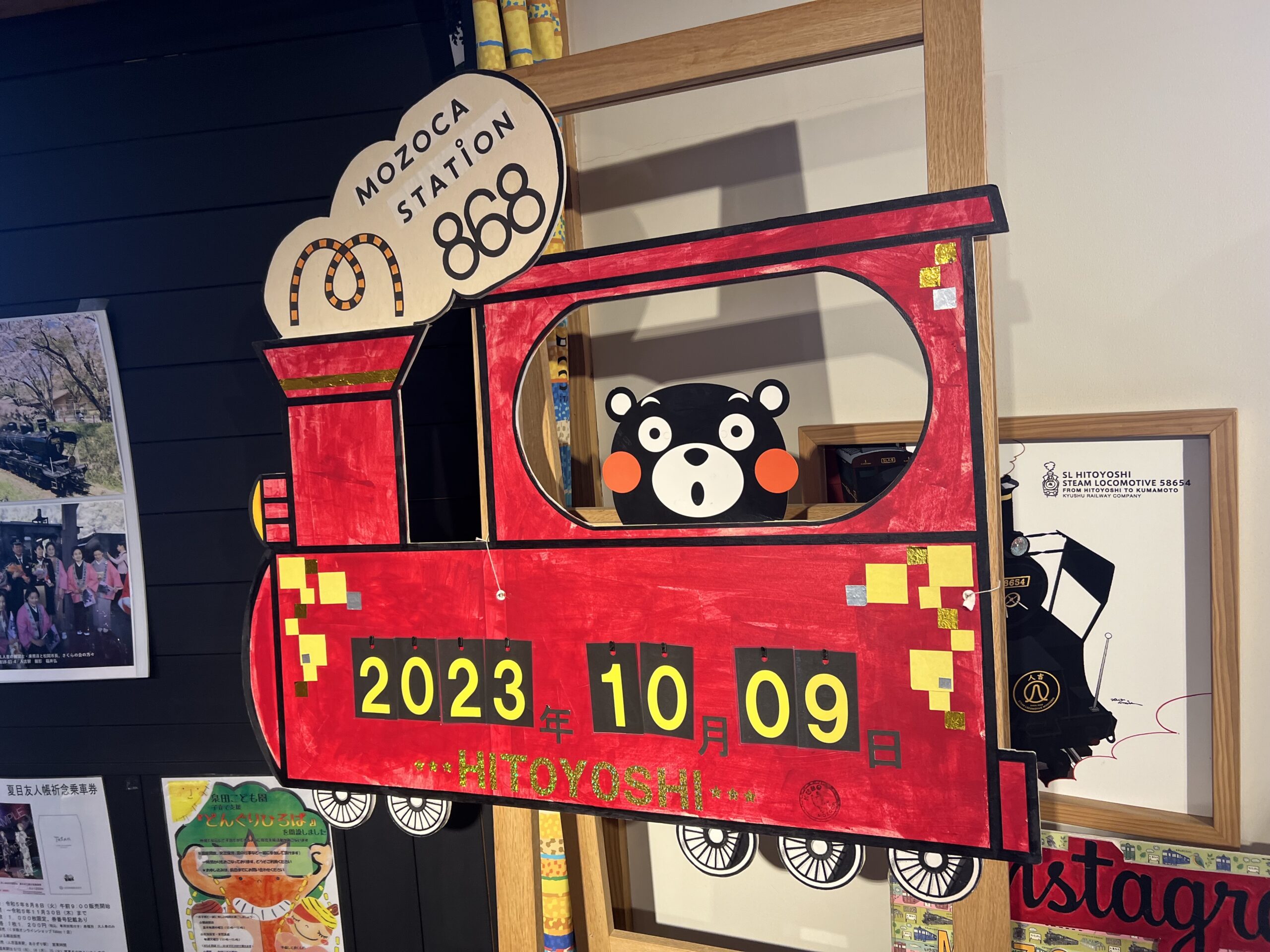 熊本県人吉市にあるMOZOCAステーションにて撮影した写真。 熊本県のゆるきゃらであるくまモンが汽車に乗っているイラストに、撮影した日付が書かれている看板が写っている。 撮影日は2023年10月9日。